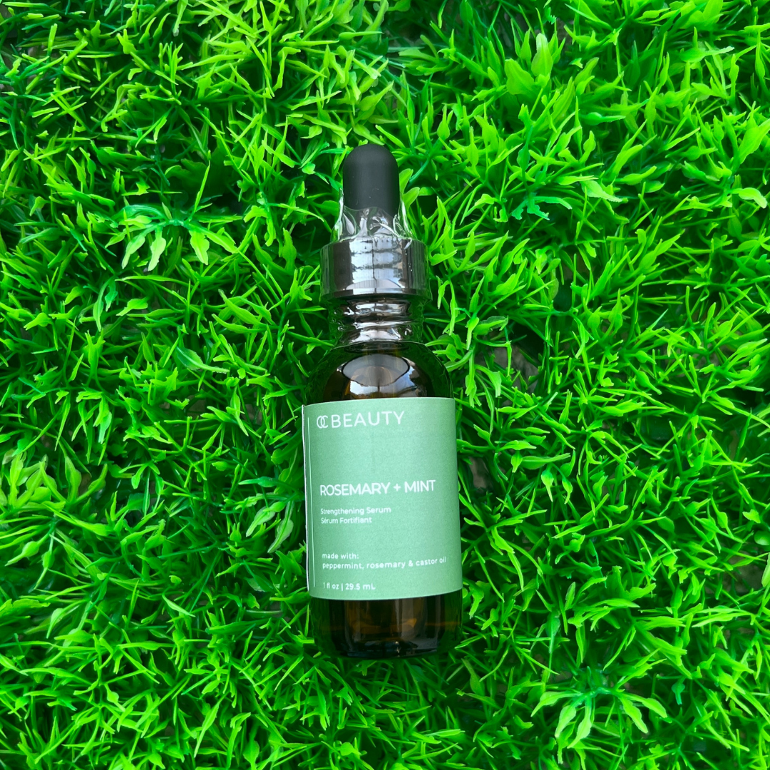 OC Beauty Co. Rosemary and peppermint hair oil bottle with fresh rosemary and peppermint sprigs, showcasing natural hair care ingredients.